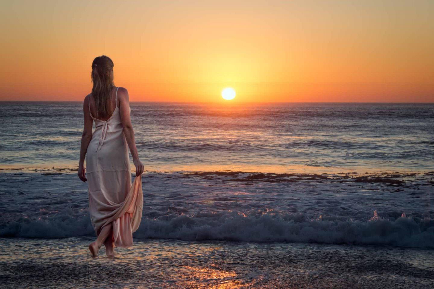 A beautiful lady in a satin dress admires a La Jolla California sunset